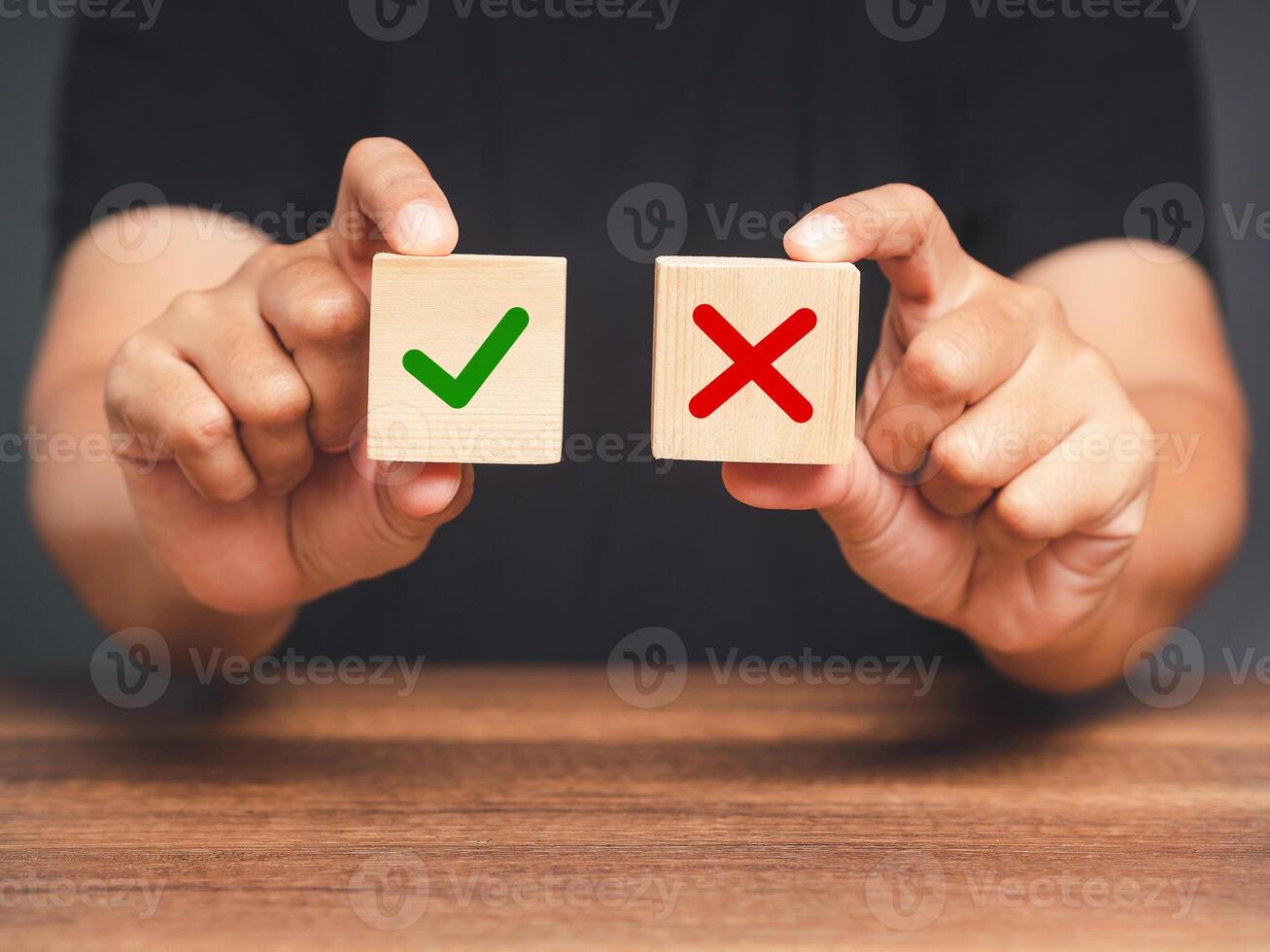 Hand holding two wooden cubes with a green checkmark and red cross photo