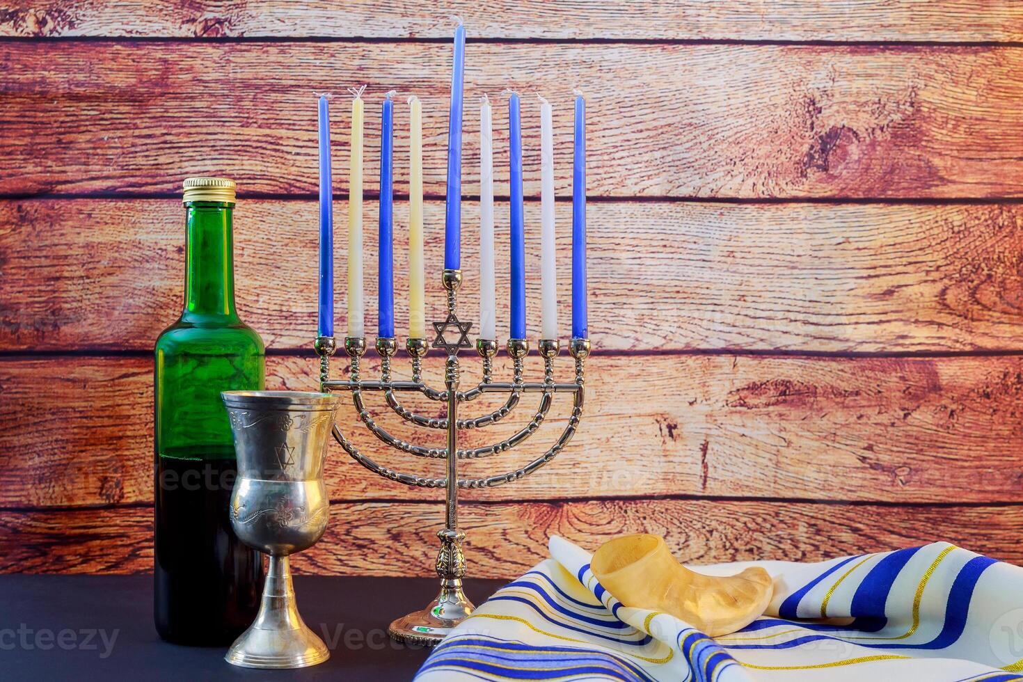 Beautiful lit hanukkah menorah on black background. Jewish holiday Hanukkah wine talyt photo