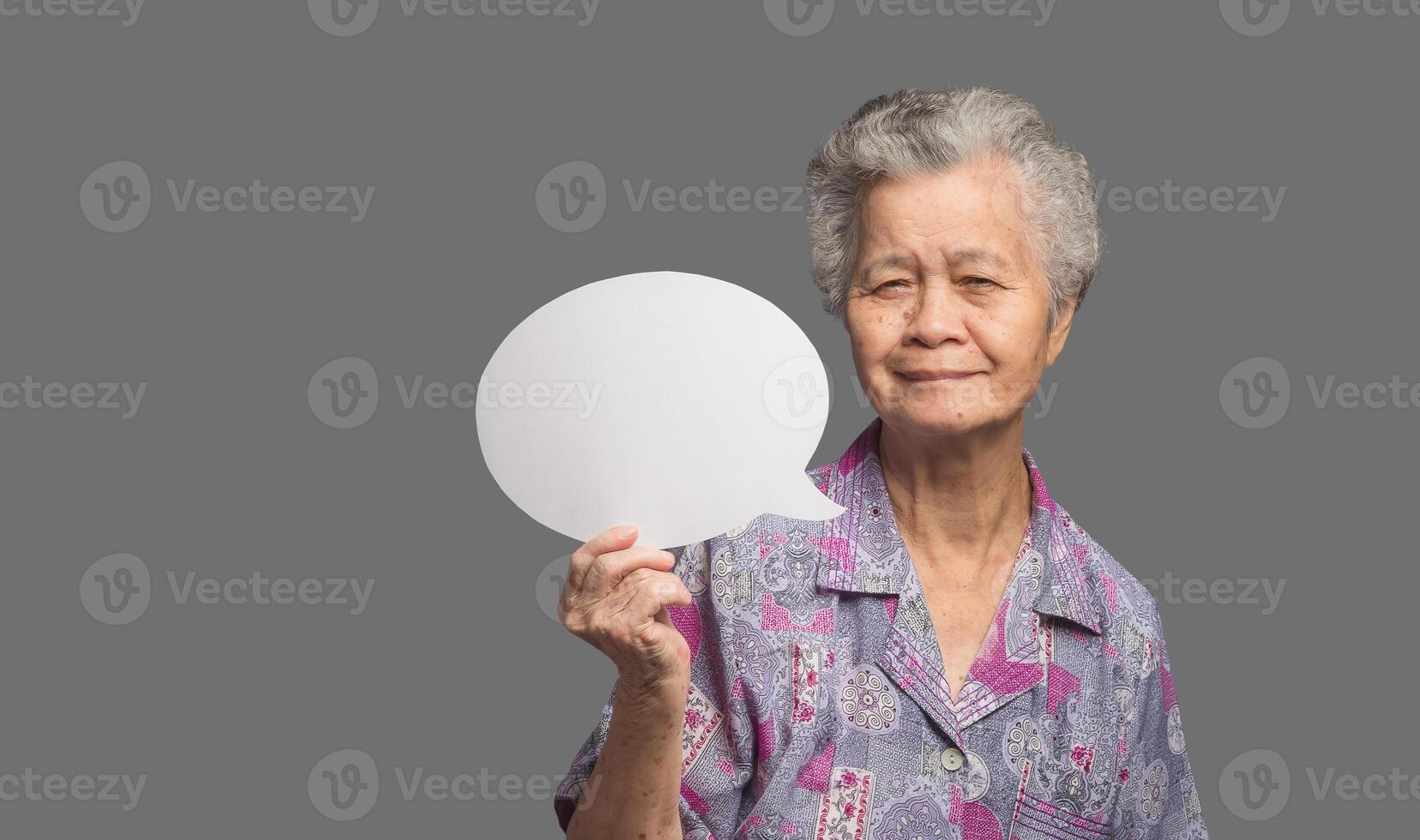 Senior woman holding a blank speech bubble and looks at the camera with a smile photo