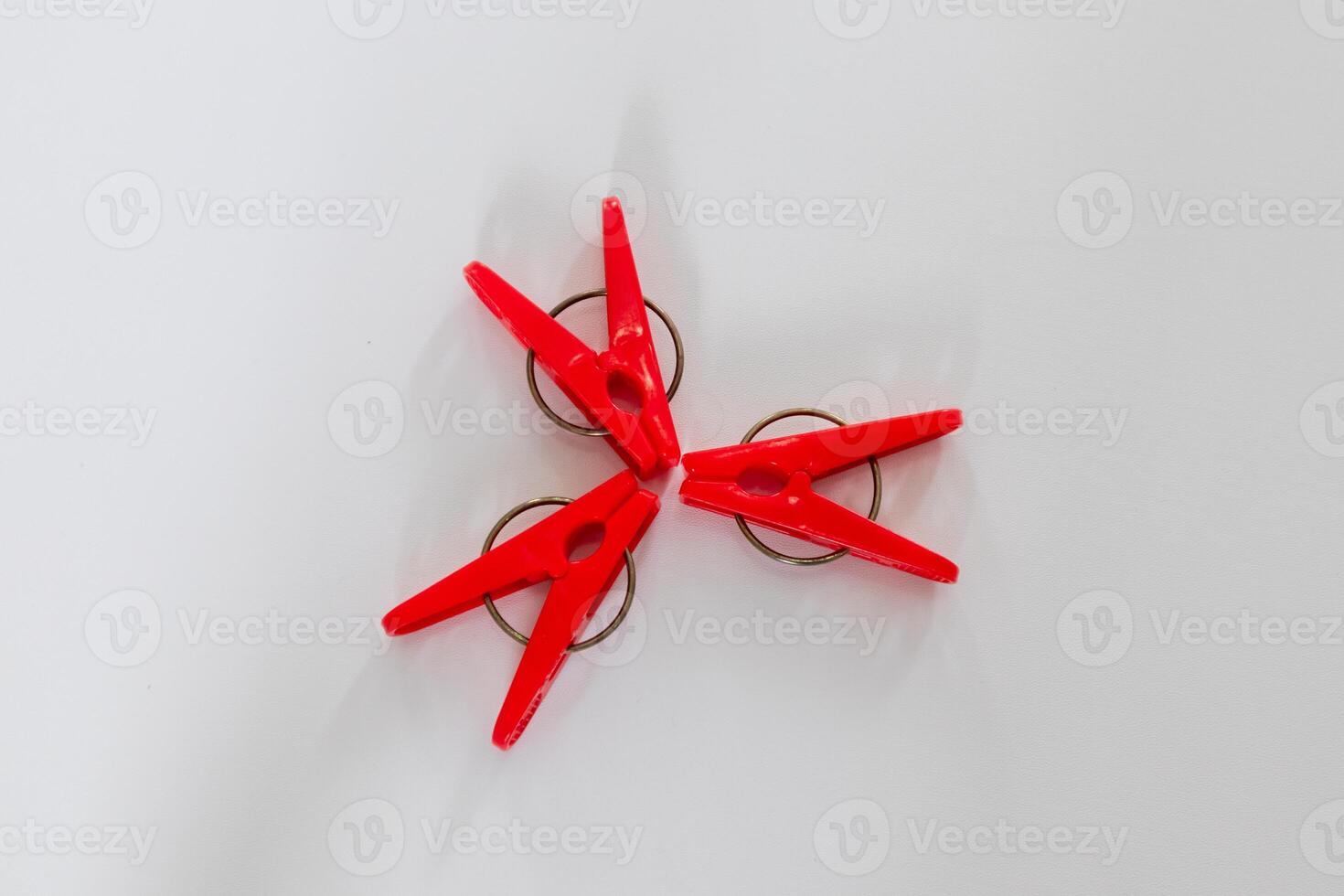 Three red clothes pegs on a white background photo