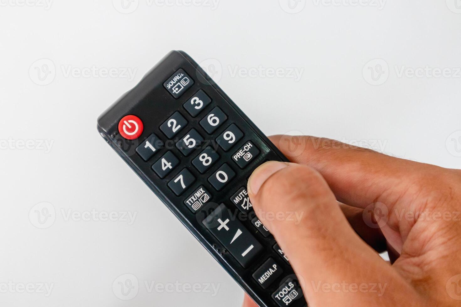 Hand holding a tv remote with many buttons on white background photo
