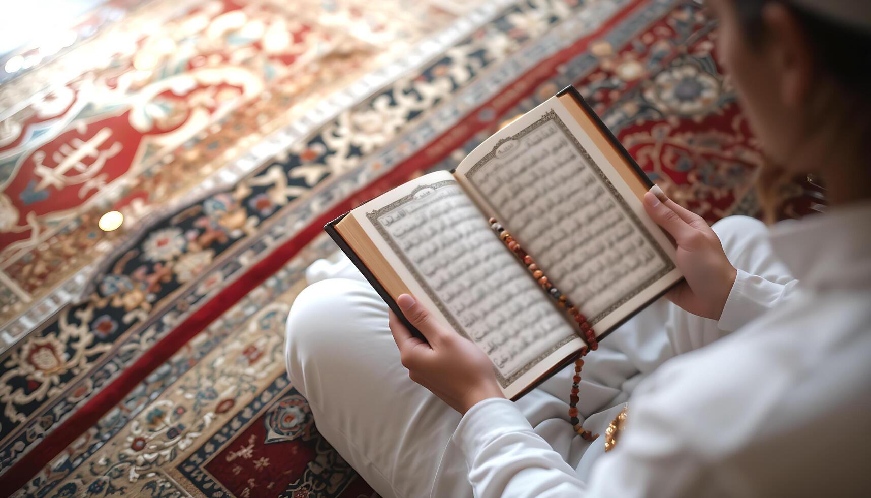Person Reading the Quran with Prayer Beads on an Intricately Patterned Carpet in Mosque photo