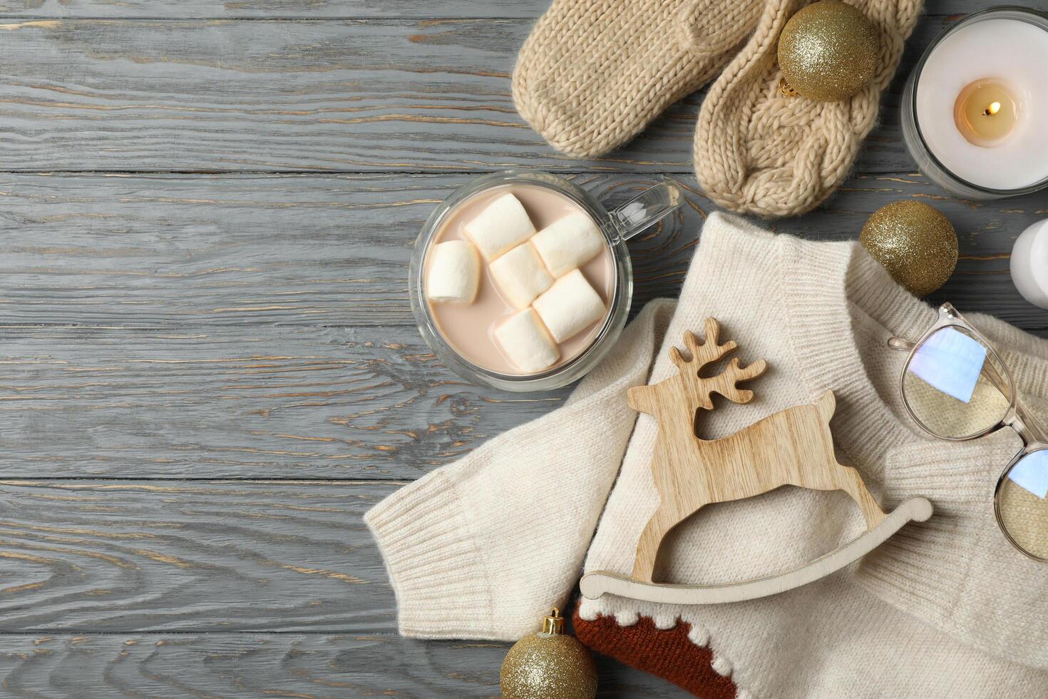 Winter concept with coffee with marshmallow, sweater and candles on wooden background photo