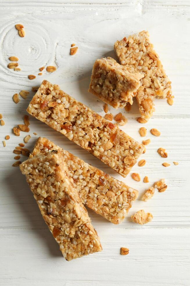 Tasty granola bars on white wooden background photo