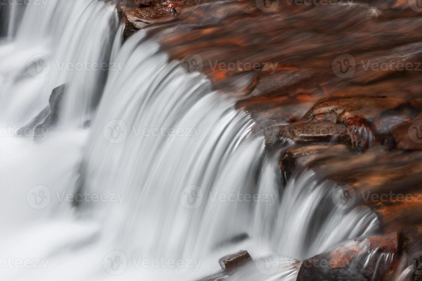 A waterfall is flowing over rocks photo