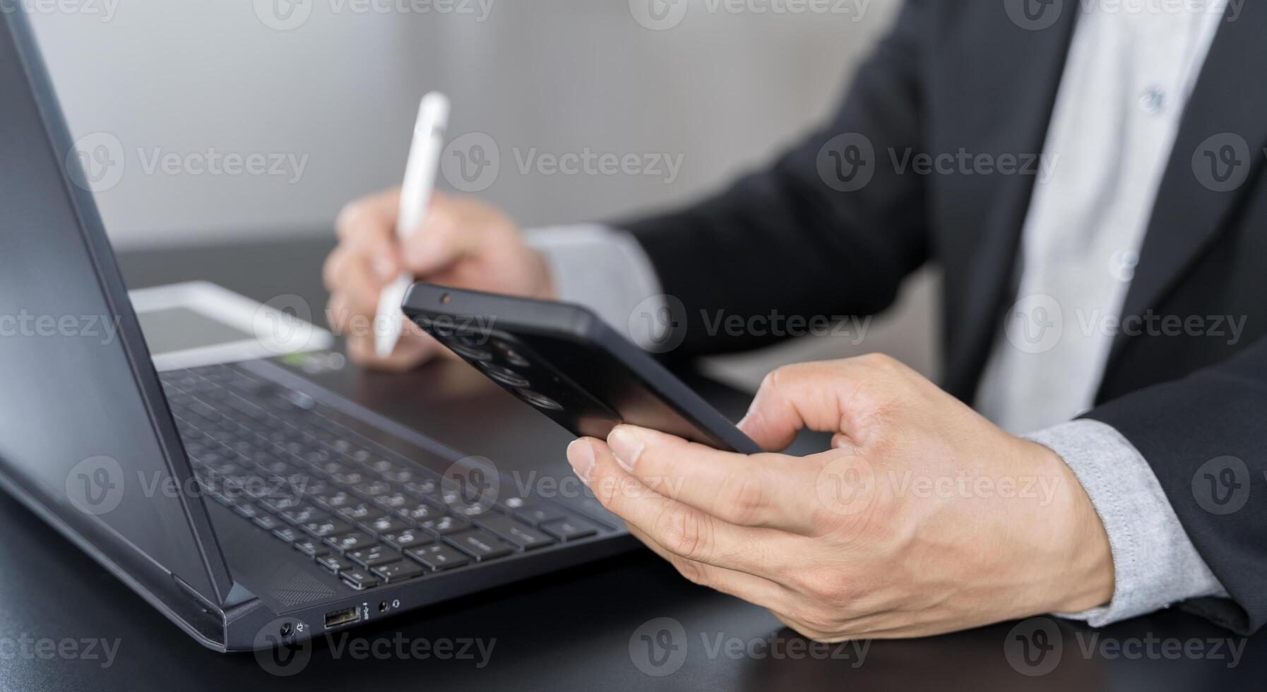 Businessman using mobile smart phone and online working on laptop computer photo