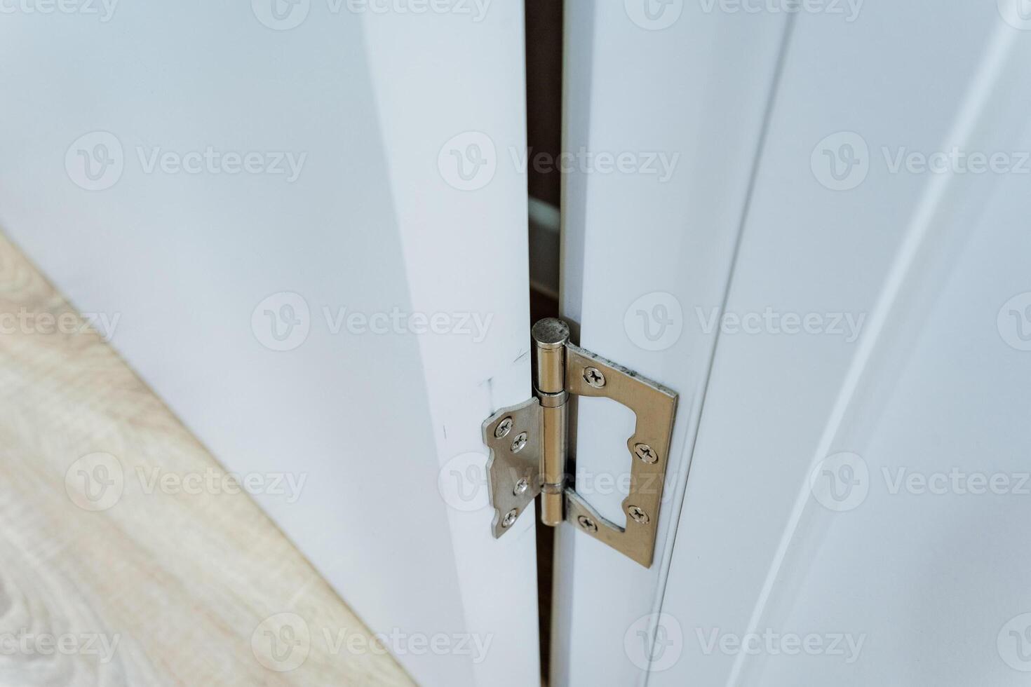 A detailed closeup shot of a white door that features a damaged or broken hinge, highlighting the wear and tear often found in household doors and the importance of proper maintenance photo