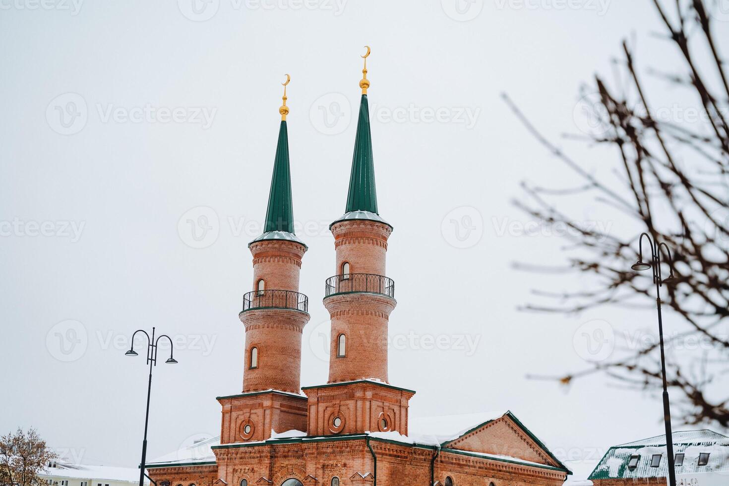 A majestic brick building featuring two tall minaret towers is beautifully adorned in a layer of snow, creating a picturesque winter scene that captivates the viewers imagination photo