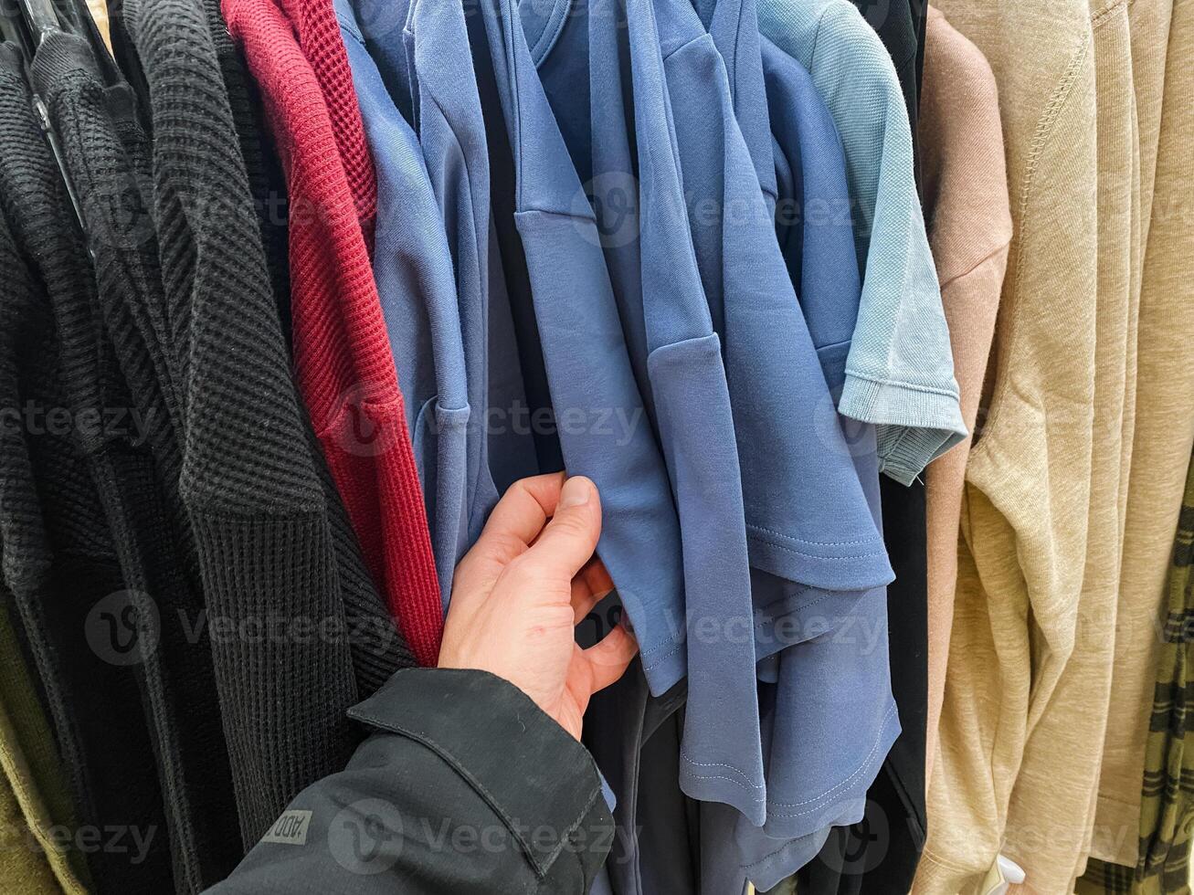 A person is currently holding a blue shirt in their hand, displaying an interest in fashion and clothing, perhaps considering styling it for an upcoming event or occasion photo