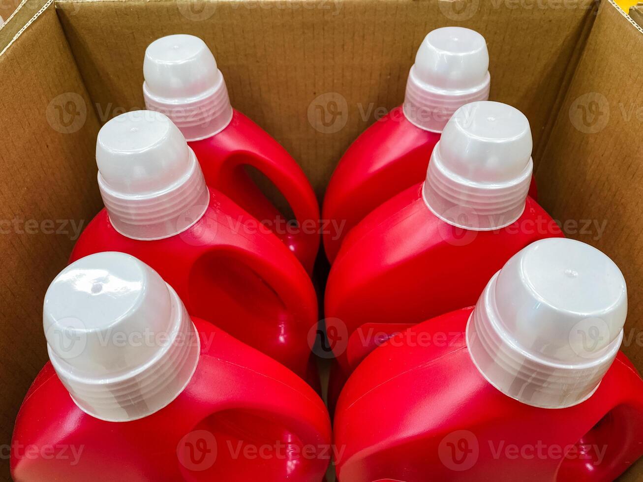 Inside a sturdy and wellconstructed box, there are four vibrant red bottles with shiny white caps, securely stored and meticulously prepared for transport to carry various types of liquids photo