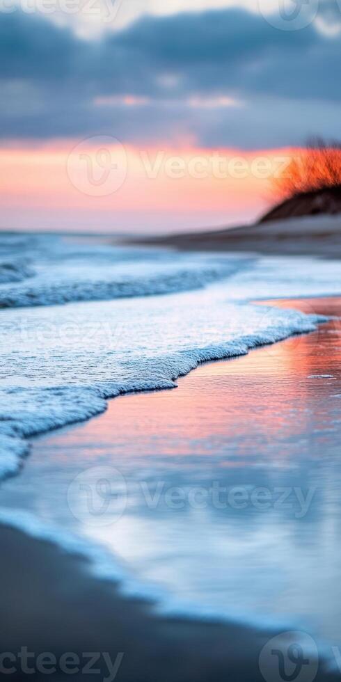 A beautiful sunset over the ocean with a tree in the background. The water is calm and the sky is a mix of orange and pink hues photo