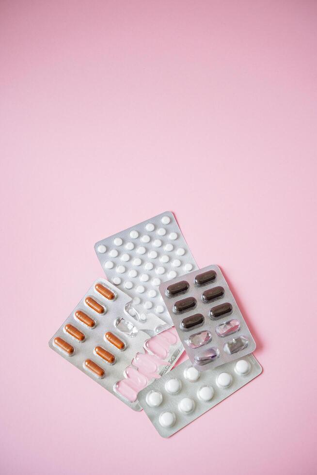 This colorful collection features various blister packs of pills, carefully arranged against a vivid pink background, creating a striking visual contrast that grabs attention photo