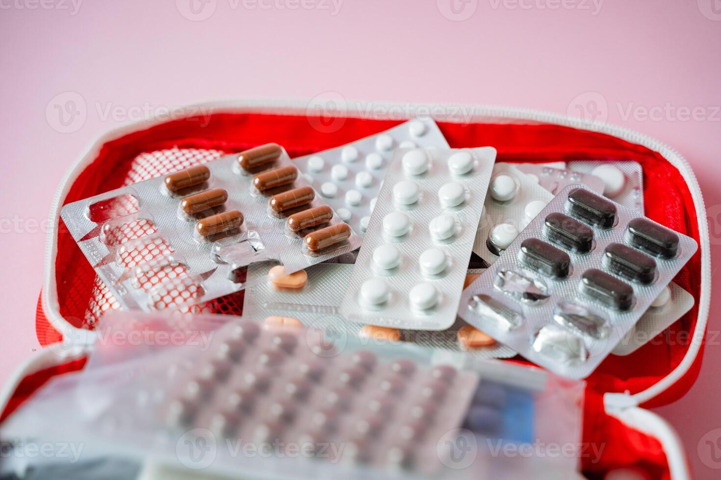 A bright red first aid kit that contains an assortment of various pills and capsules, designed for medical emergencies and health care needs, ensuring you have essential medicines on hand photo
