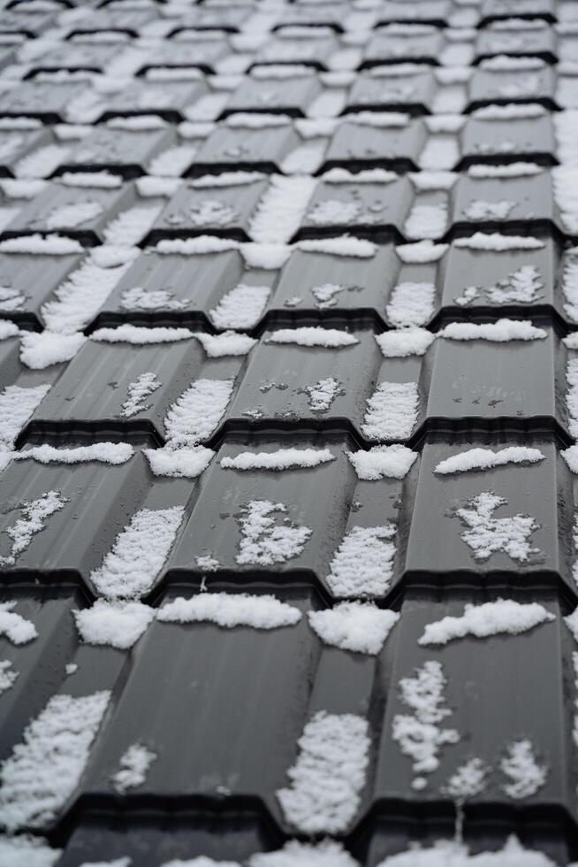 This striking black and white photo beautifully captures a snowcovered roof, skillfully emphasizing the stark contrasting colors and intricate textures of a tranquil winter scene
