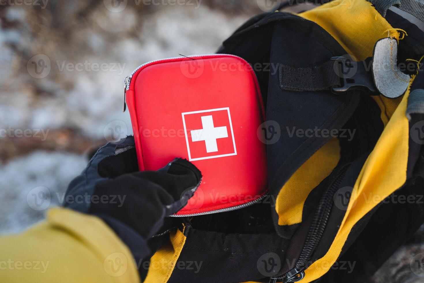 A person is carefully placing a first aid kit into their backpack, ensuring that they have all necessary supplies for any potential emergencies while enjoying their outdoor activities photo