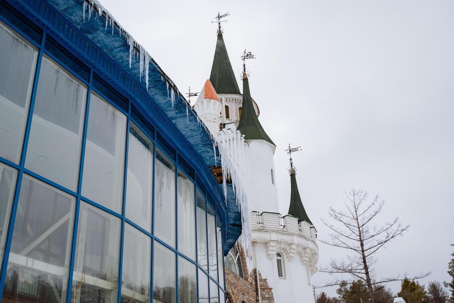 Imagine a magnificent building that prominently features a castle perched atop it, complete with beautiful icicles gracefully forming along the edges of the roof in the winter photo