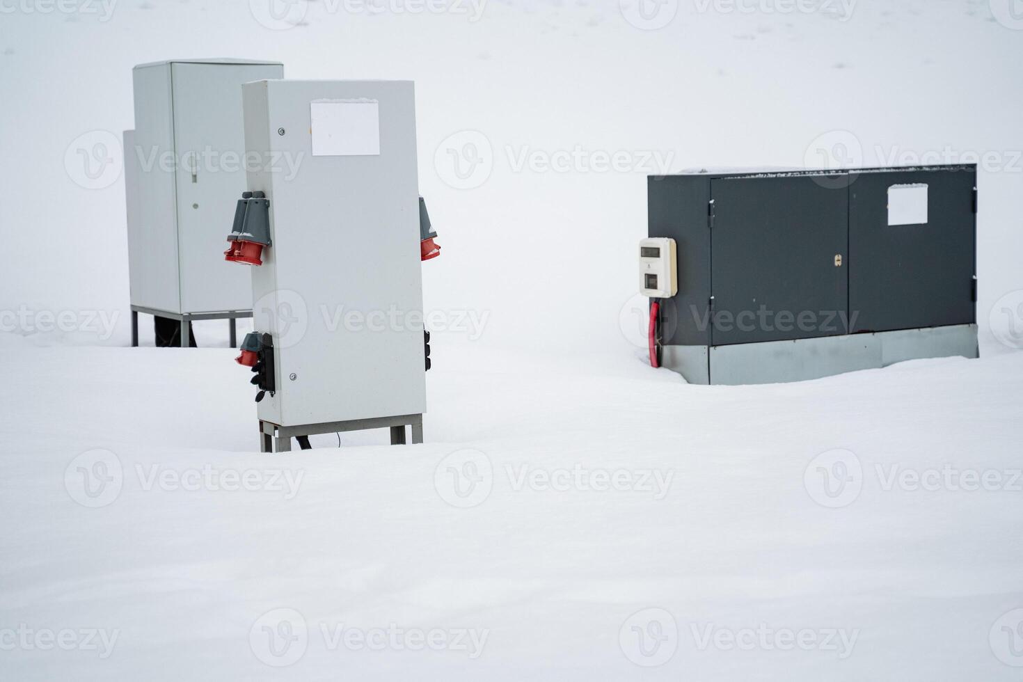 Three electrical boxes are currently positioned in the snow, with their surfaces covered in a layer of white frost, reflecting the cold, winter atmosphere all around them photo