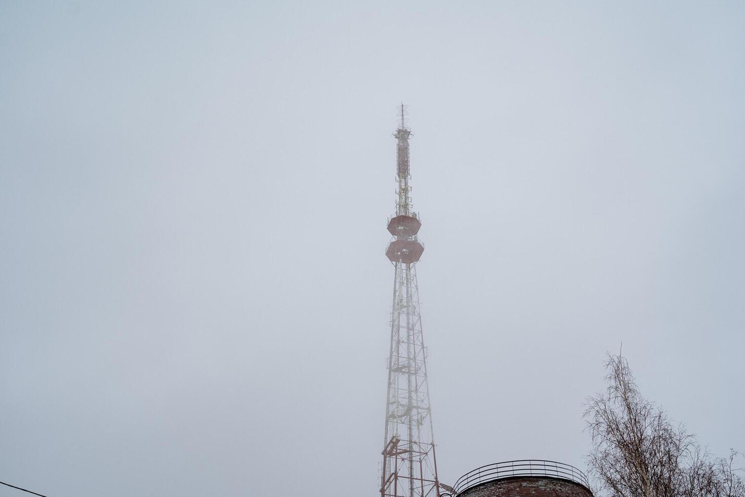 A very tall tower stands majestically against a backdrop of a cloudy sky, showcasing its significance in telecommunications and its role as a transmitter station for cellular networks photo
