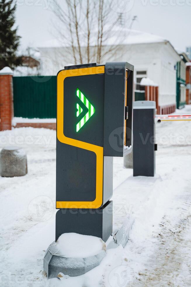 A parking meter stands visibly under the harsh winter conditions, marked with a distinct green arrow, indicating availability despite the ongoing snowfall and freezing temperatures photo