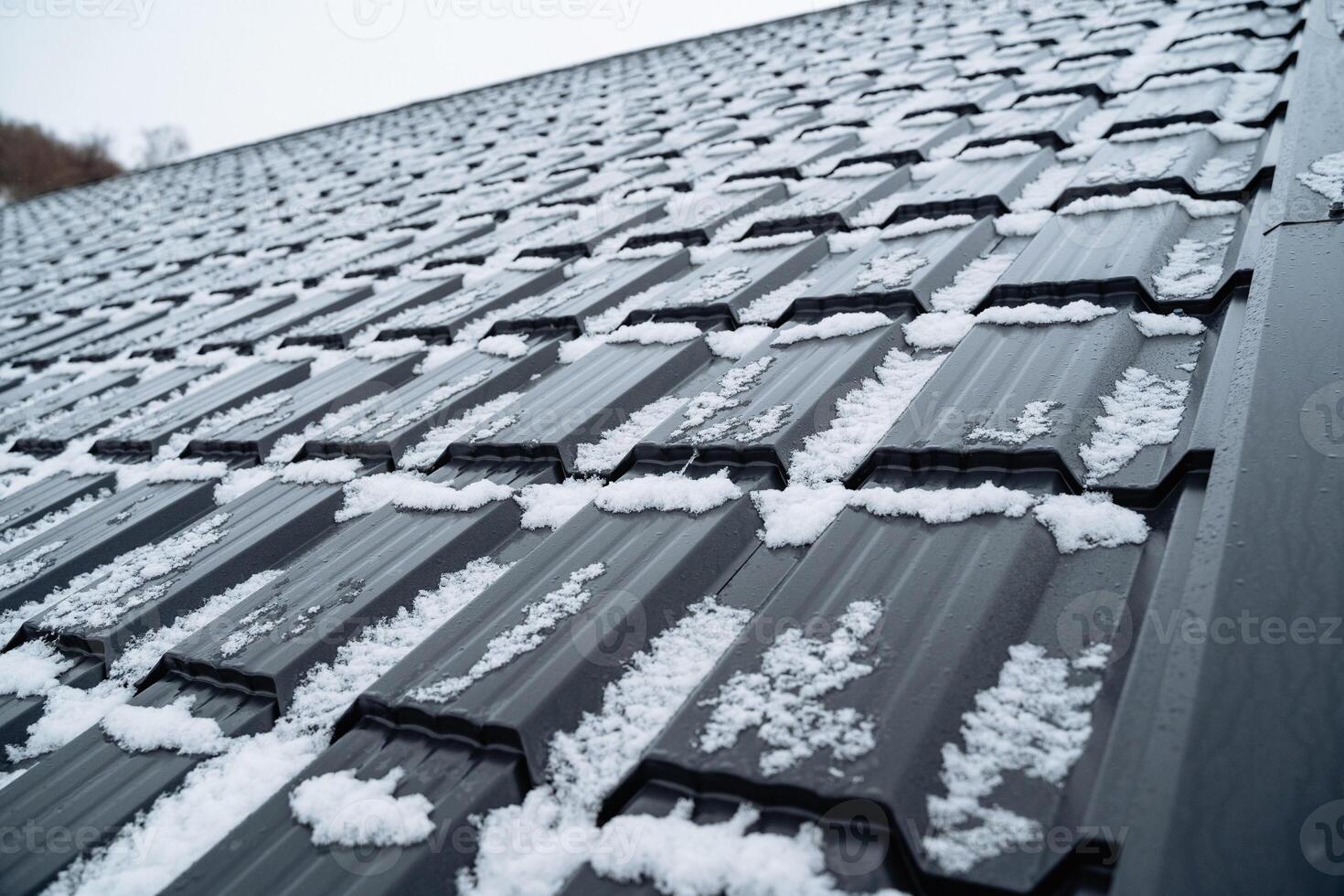 This image features a detailed closeup view of a roof that is adorned with a thick, soft layer of fresh snow, significantly enhancing its charming and picturesque winter appearance photo