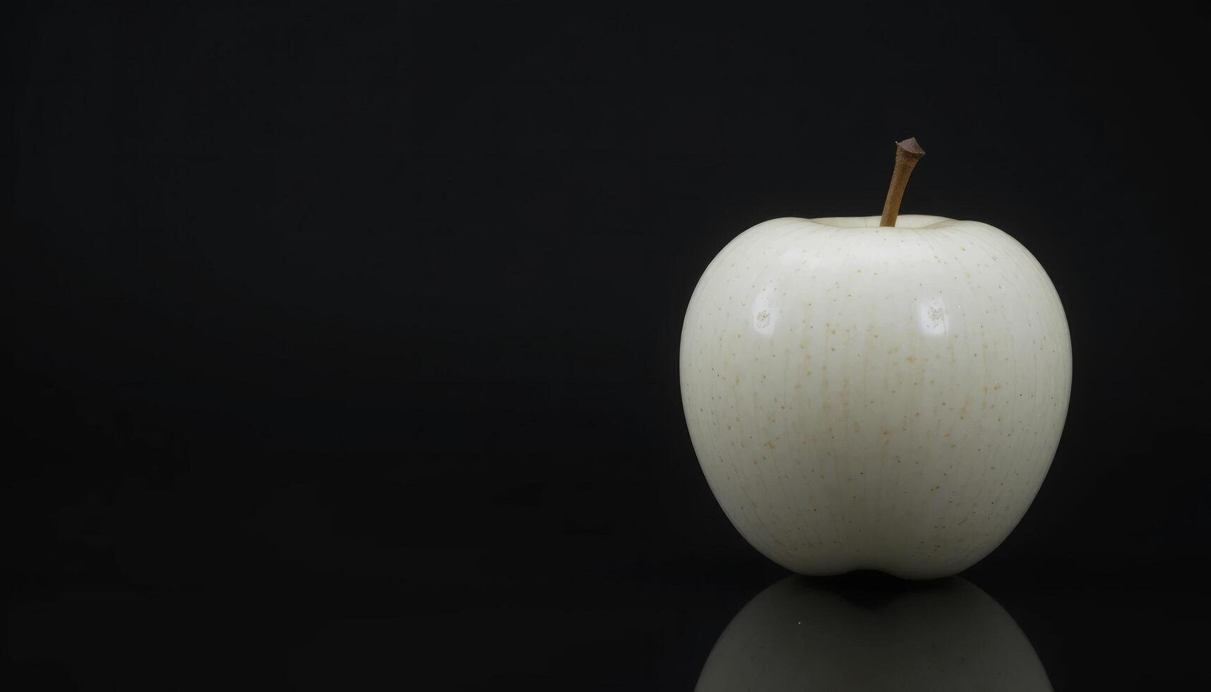 A Single White Apple Against a Black Background. A Study in Contrast and Minimalism photo