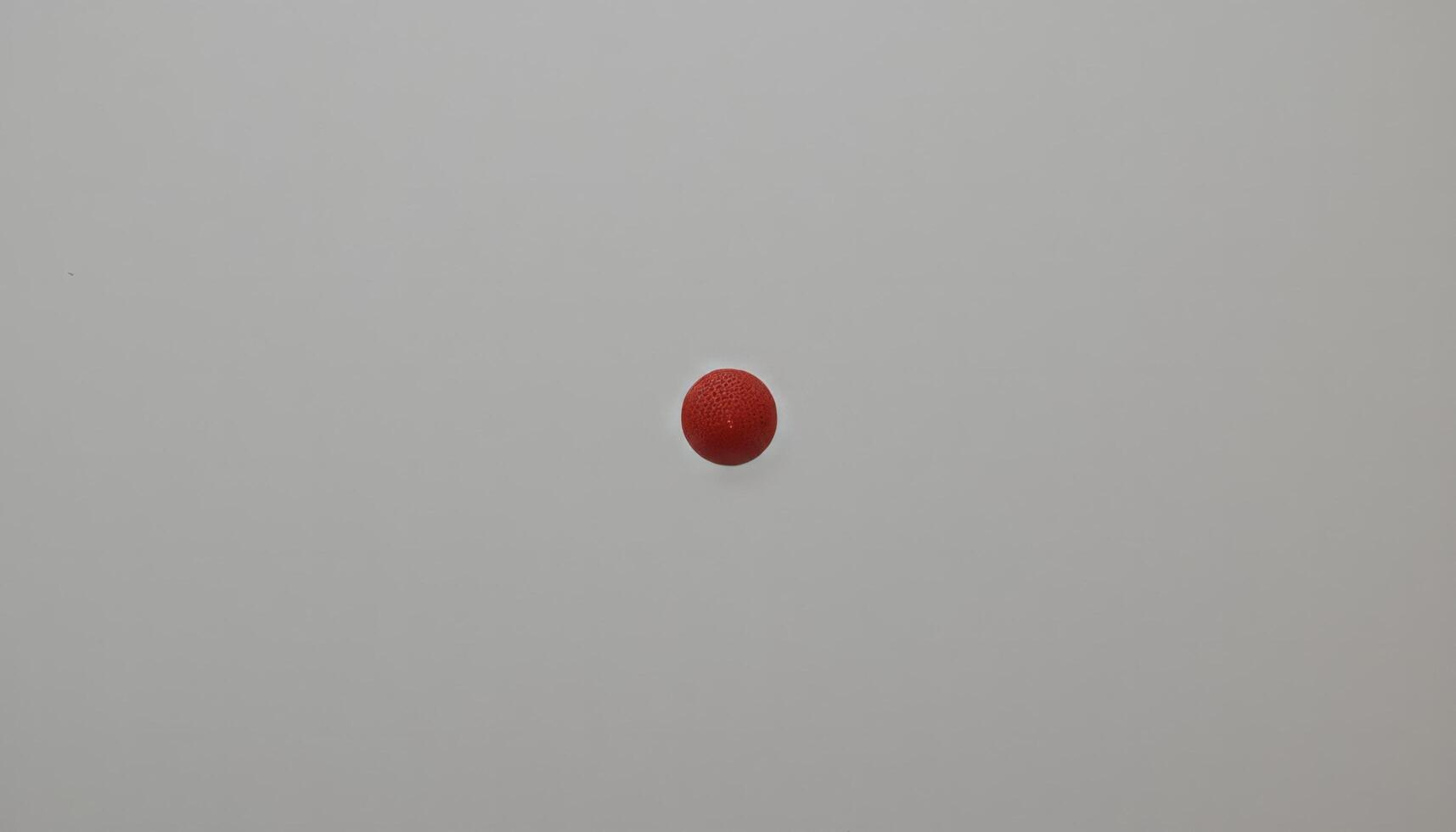 A Single Red Sphere Against a Neutral Background. Minimalist Photography Study photo
