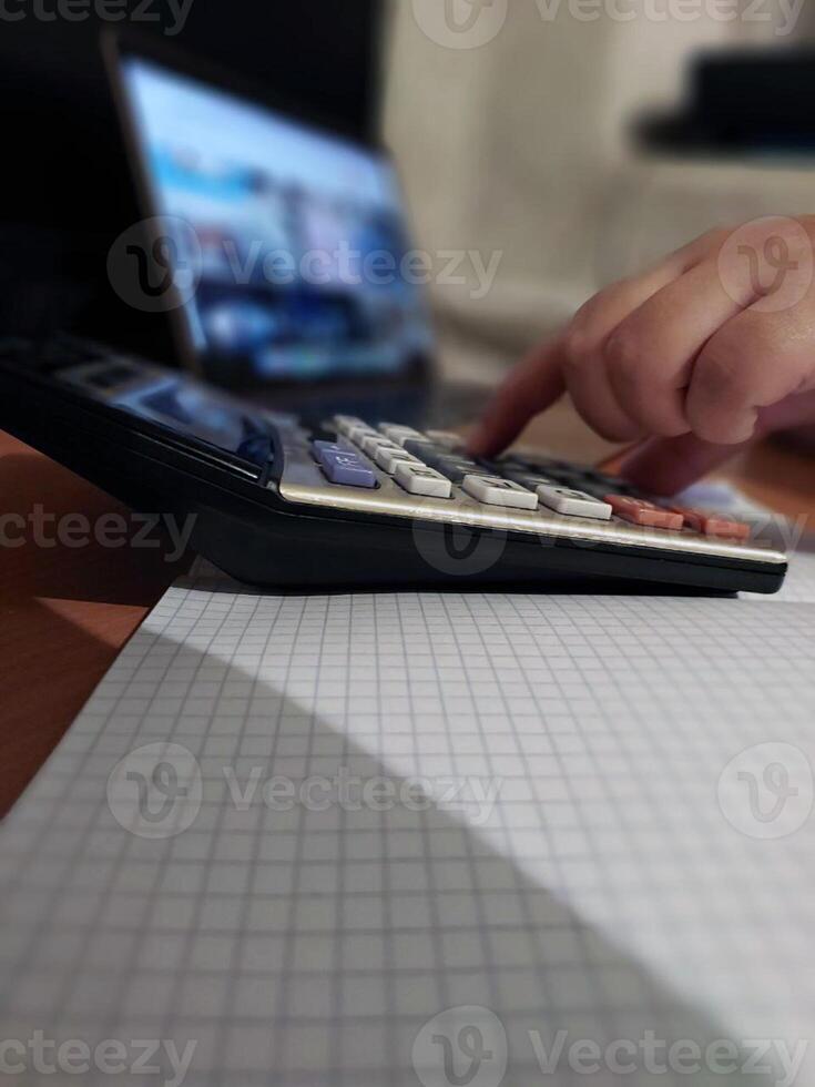 Person calculating on scientific calculator with graph paper on desk photo