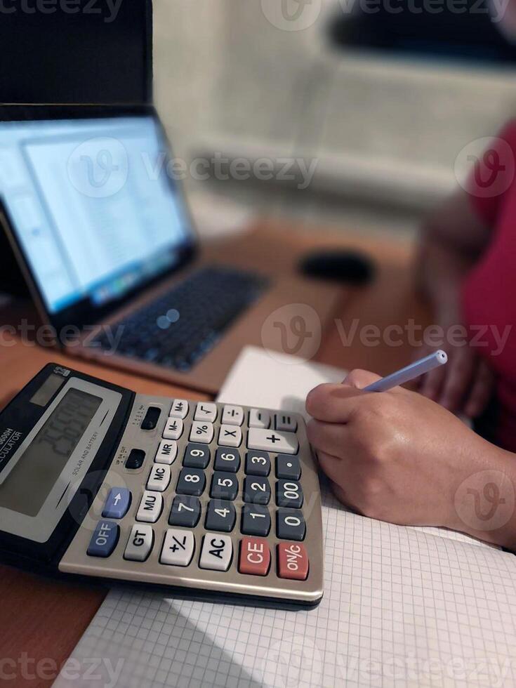 Female calculating finances with laptop and calculator on desk photo