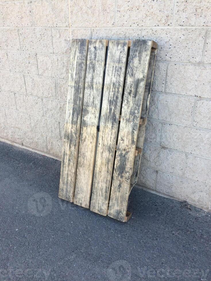 Wooden Pallet Leaned Up Against a Wall in a Parking Lot photo