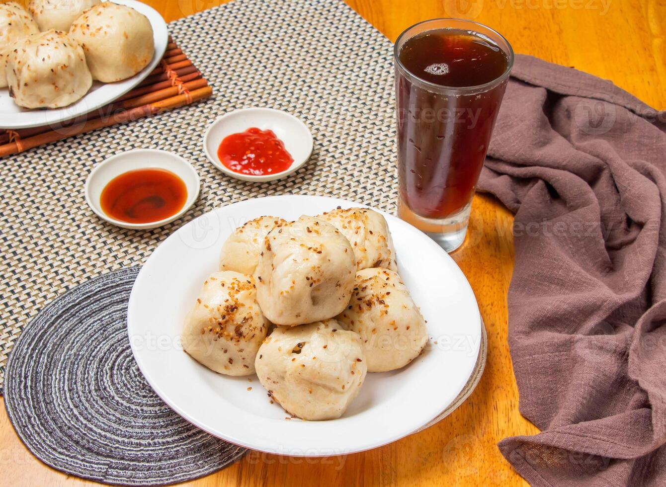 Pan Fried Buns 6 piece with Dipping Sauces and a tall glass of iced tea isolated on napkin side view of taiwan dim sum food photo