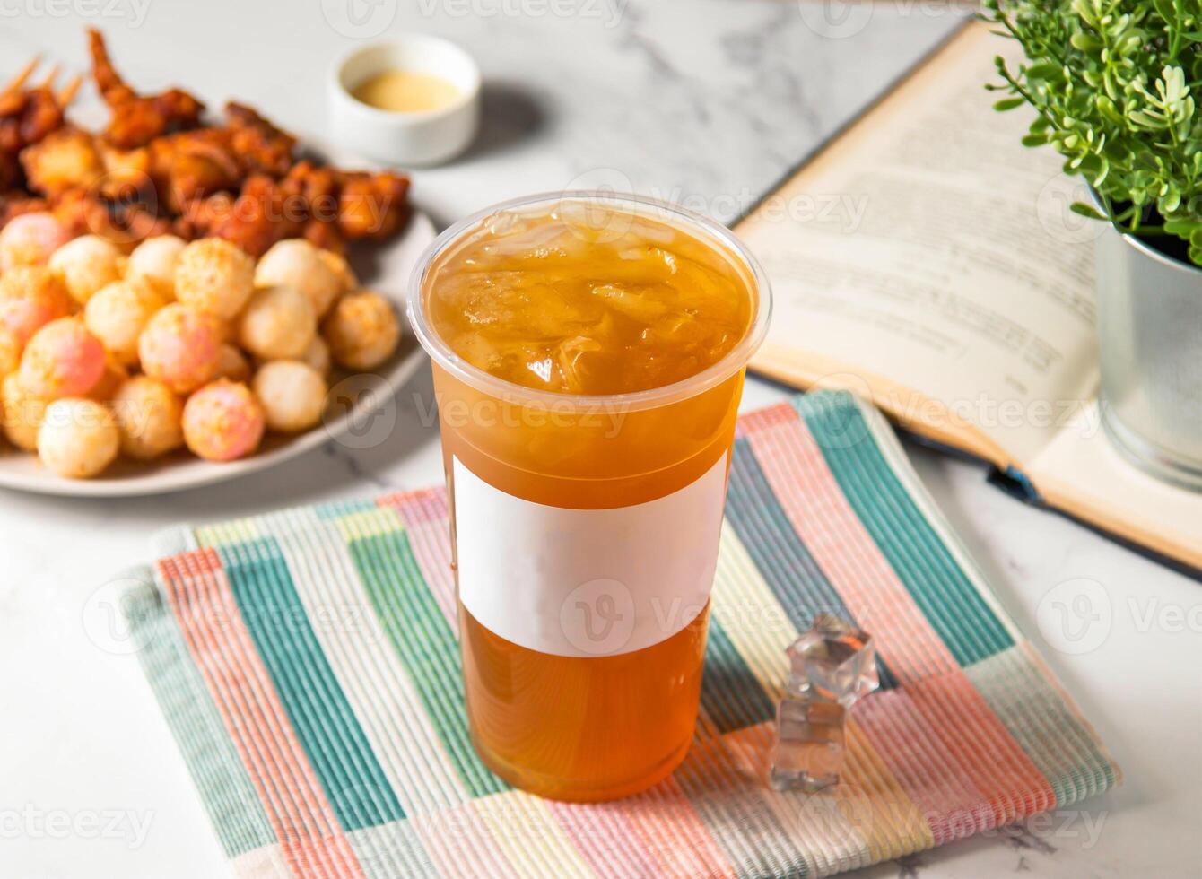 Iced green tea with ice cube served in plastic glass with ice cube isolated on napkin side view of taiwan cold drink photo