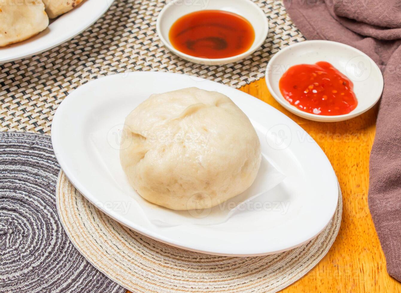 Steamed Pepper Pork Buns with Dipping Sauce served in plate isolated napkin side view of chinese dim sum food photo