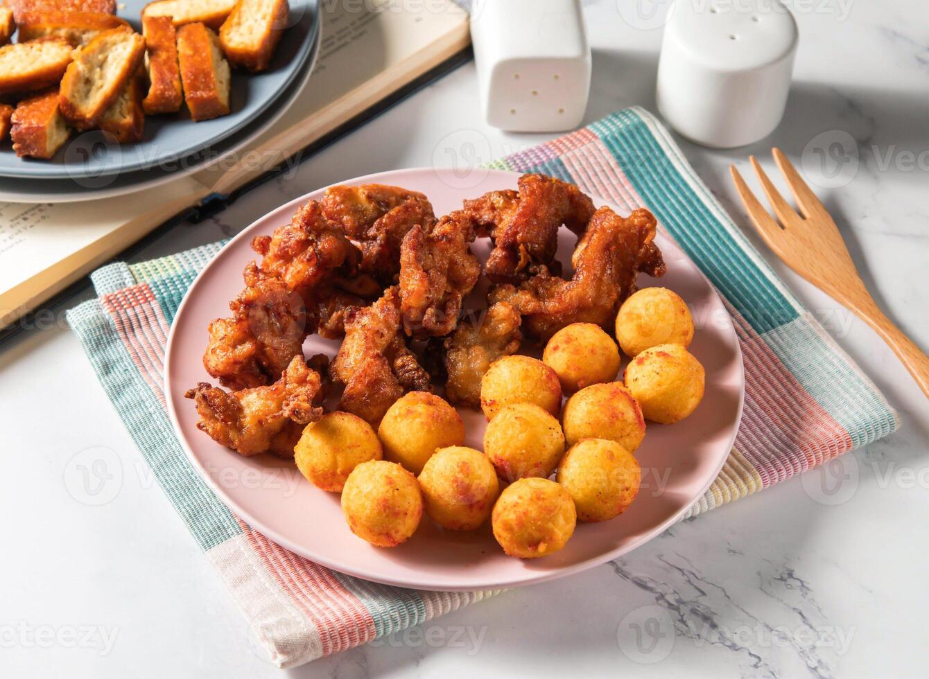Crispy Fried Chicken thigh cubes with Sweet Potato Balls and dried tofu served in plate with fork isolated on napkin side view of taiwan food photo