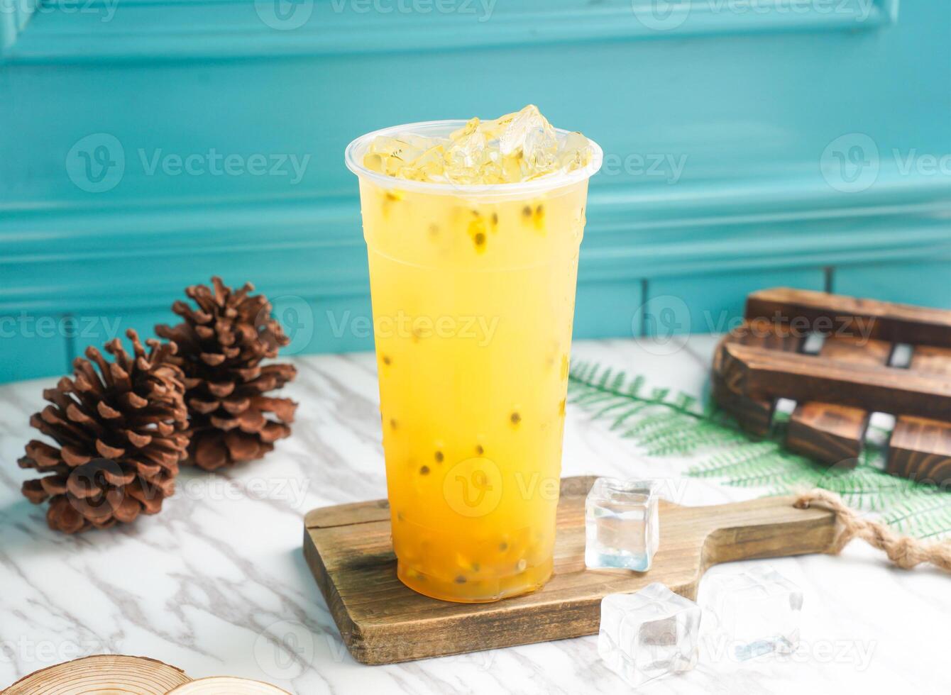 Iced Passion Fruit Green Tea with ice cube in tall glass served on a wooden board side view of taiwan cold drink photo