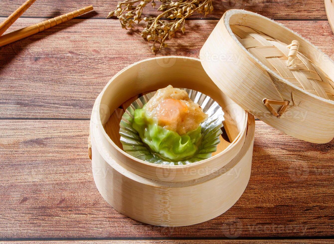 Shrimp Siew Mai Steamed Shrimp Dumpling in Bamboo Steamer with chopsticks isolated on wooden table side view of dim sum taiwan food photo