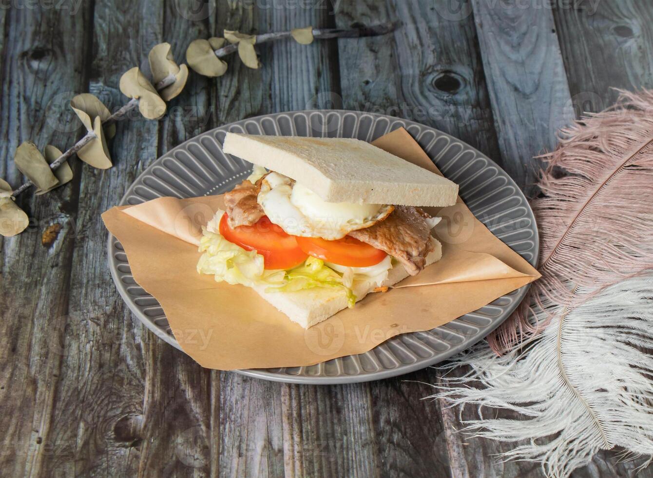 Taiwanese Breakfast Sandwich Meat and egg toast with tomato and cabbage served in plated isolated on wooden background side view of taiwan food photo