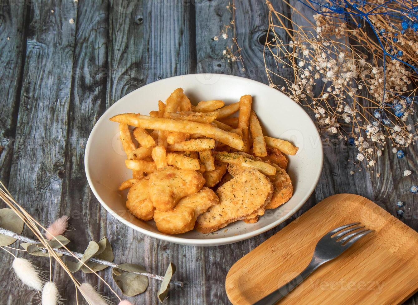 Crispy Chicken Nuggets and French Fries served in plate with fork isolated on wooden table side view of taiwan fried food photo