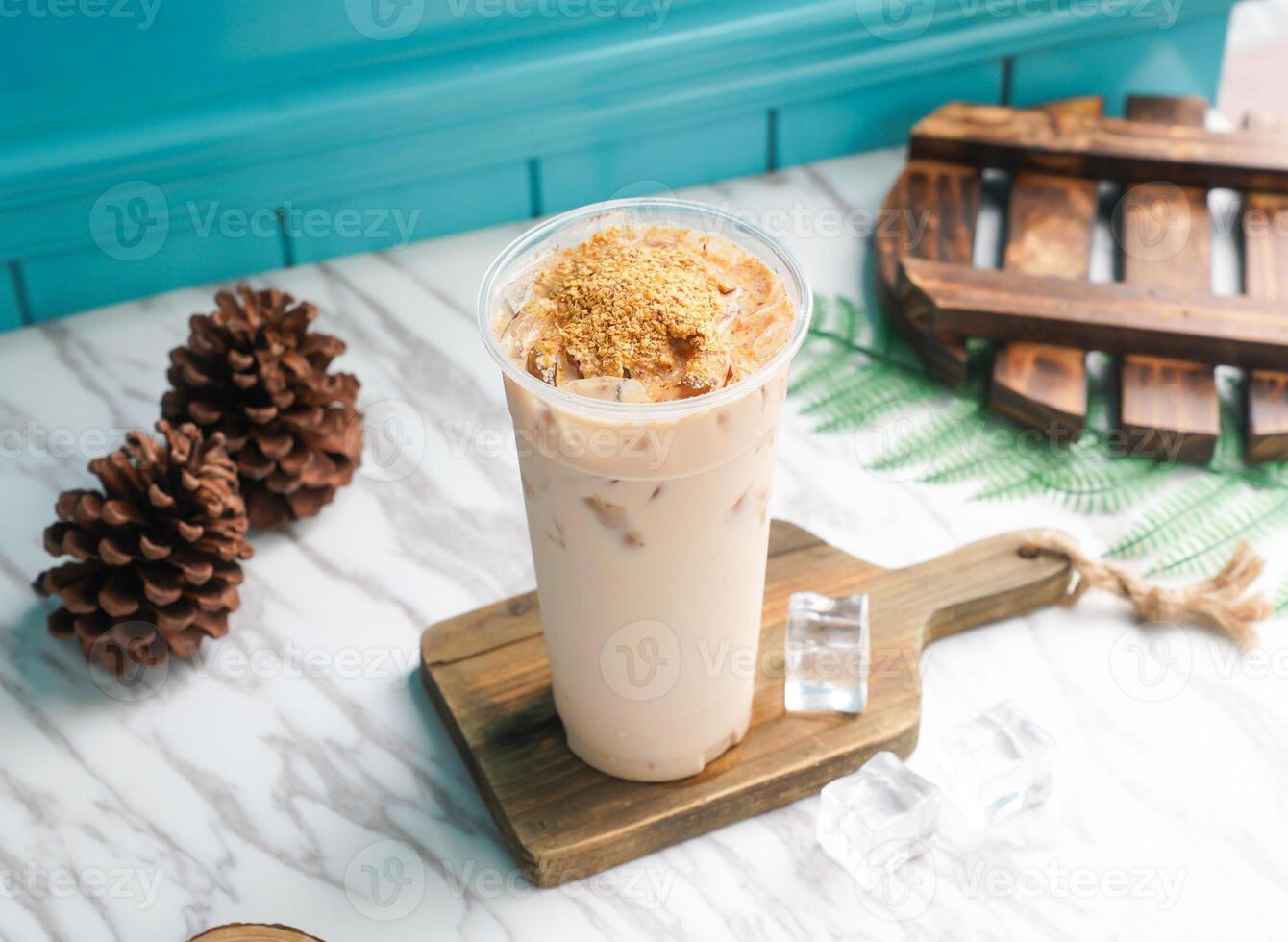 Iced Germ milk tea with ice cube in tall glass served on a wooden board side view of taiwan cold drink photo