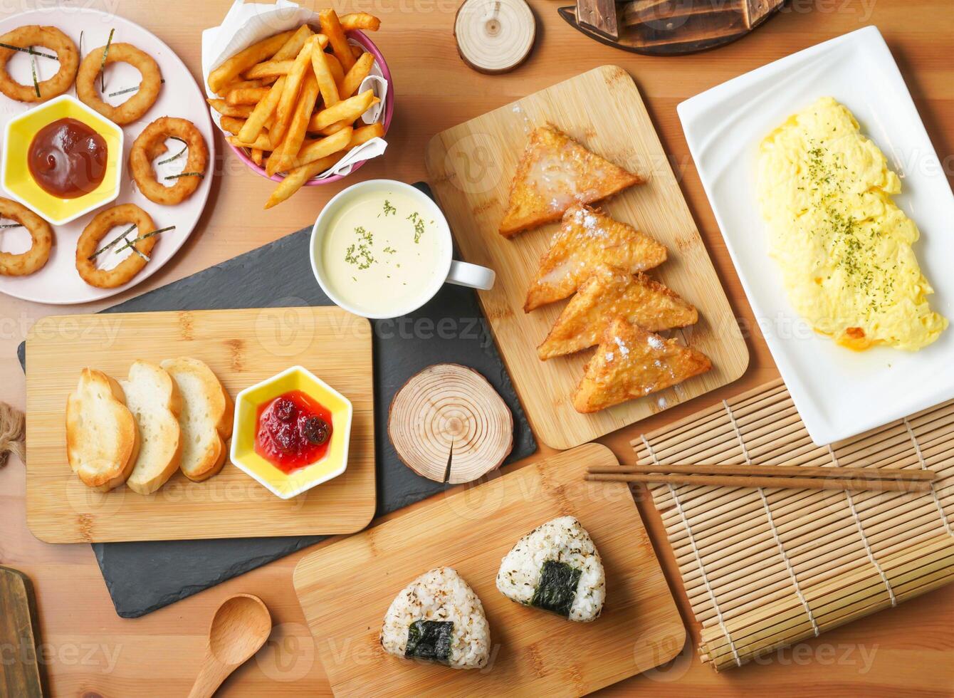 Breakfast food variety including French Toasted Bread, Crispy Onion Rings, Grilled Rice Ball, Fried French Toast, Cheese Omelette, Fries, and Creamy Corn Soup top view taiwan food on table photo
