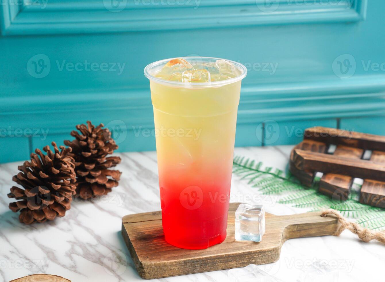 Iced Pomegranate Green Tea with ice cube in tall glass served on a wooden board side view of taiwan cold drink photo