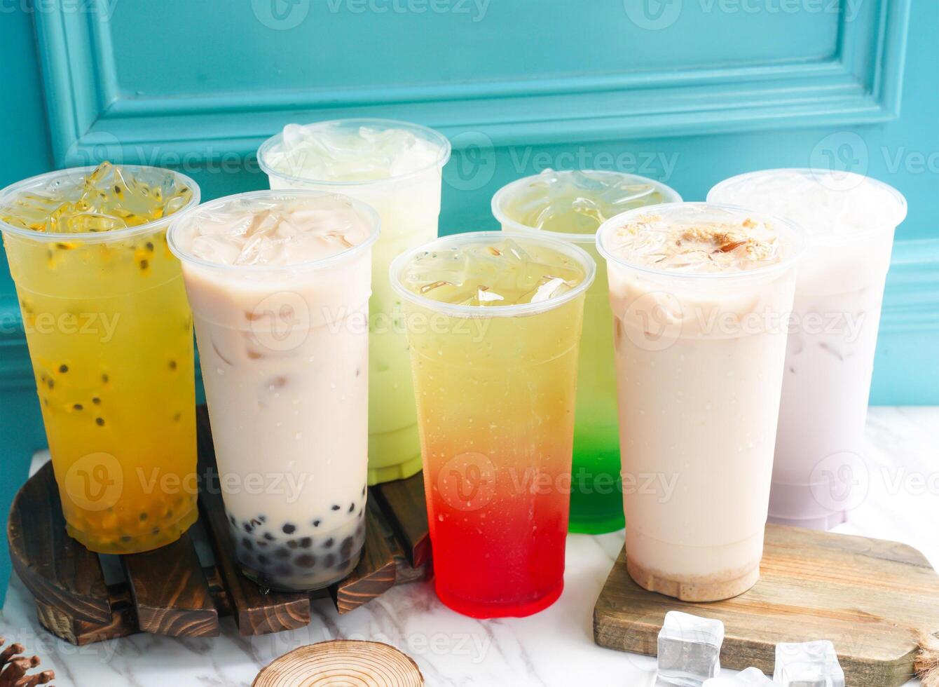 Assorted Iced Tea include Passion Fruit, Pearl, Taro, Pomegranate, mint, lime, milk, wheat, germ, and ice cube in tall glass served on a wooden board side view of taiwan cold drink photo