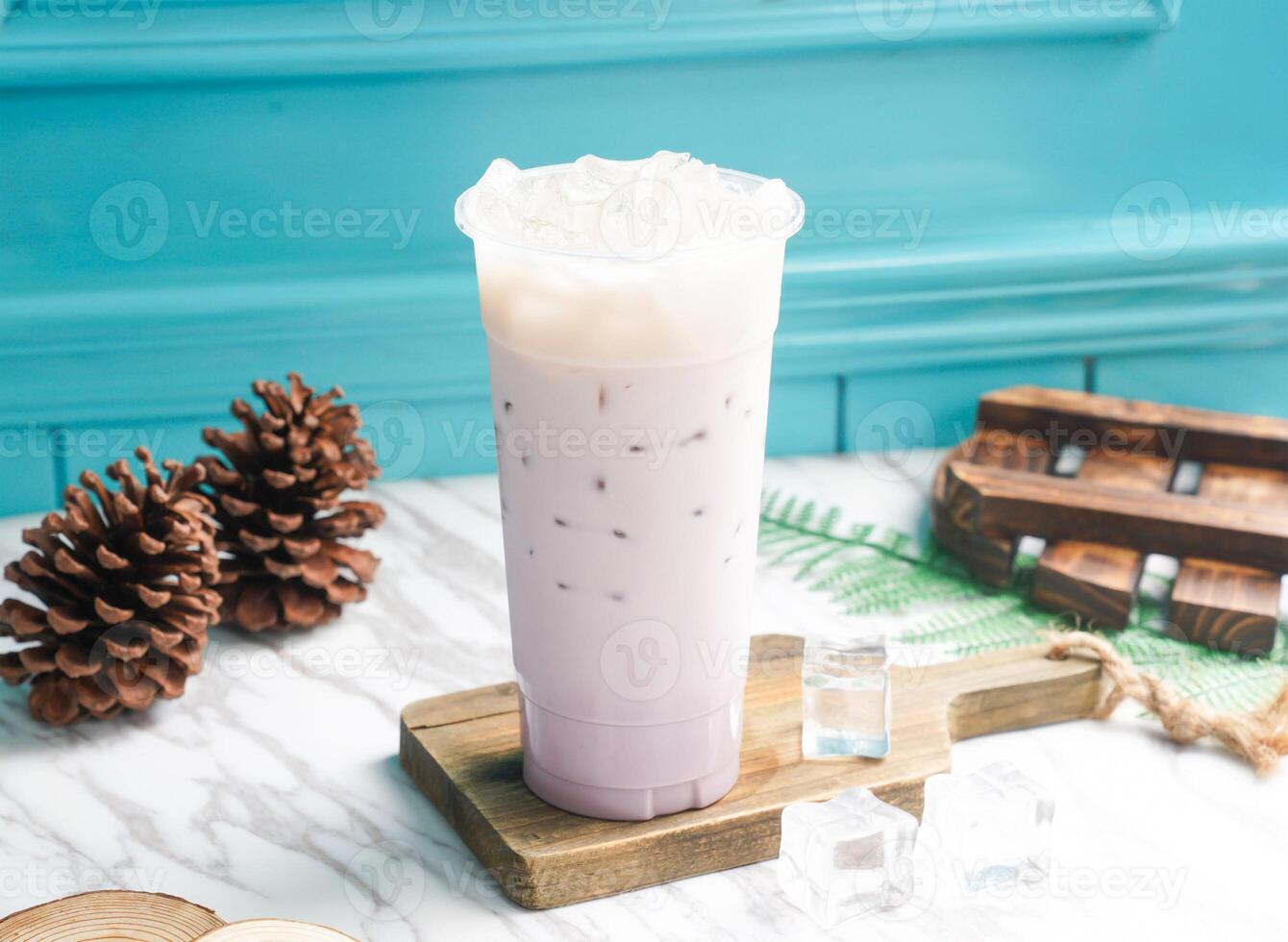 Iced Taro Milk Tea with ice cube in tall glass served on a wooden board side view of taiwan cold drink photo