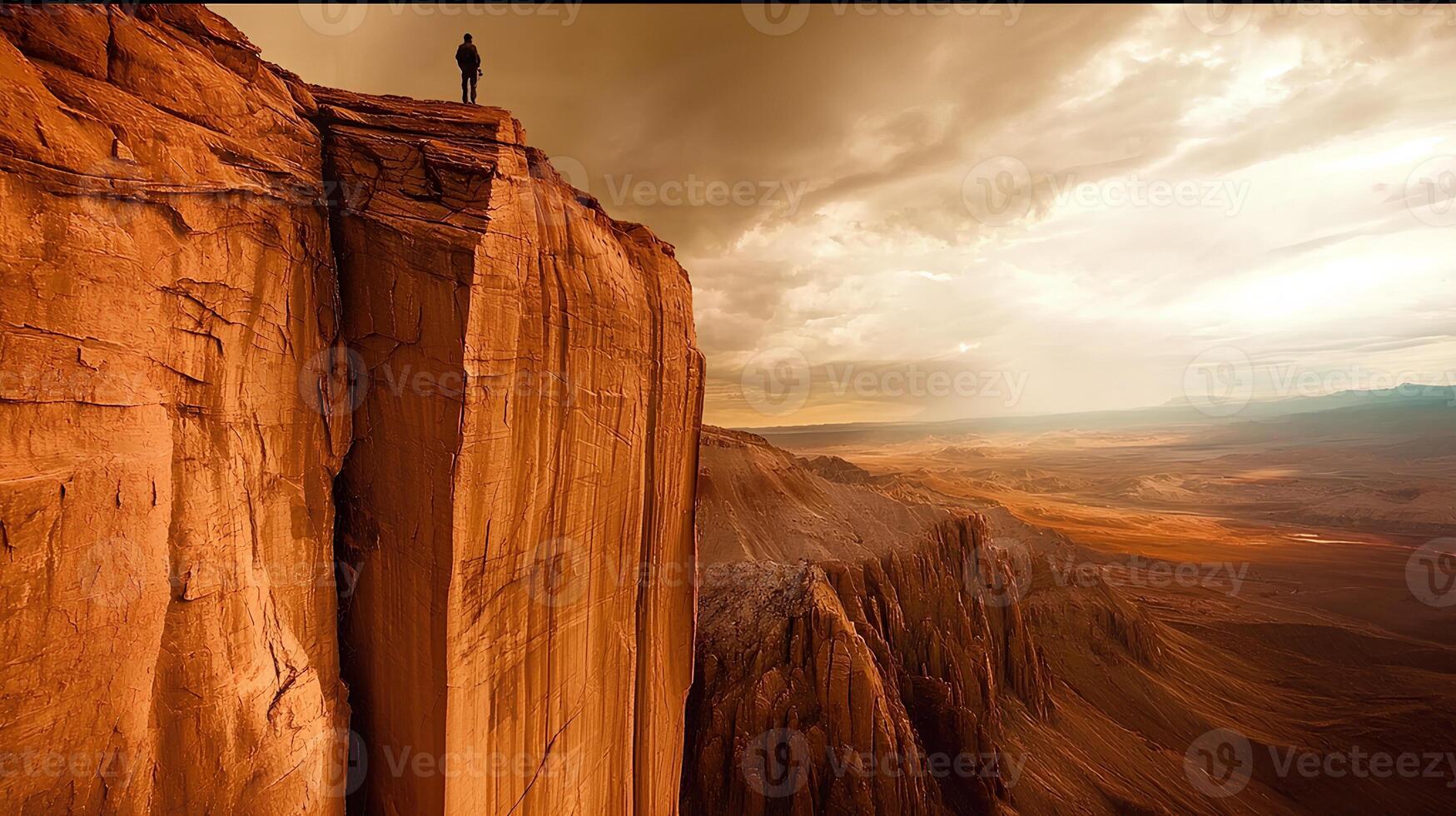 Silhouette of a man standing on the edge of a high cliff, surrounded by a stunning desert landscape. A display of nature's magnificence, vastness, and a sense of freedom. photo