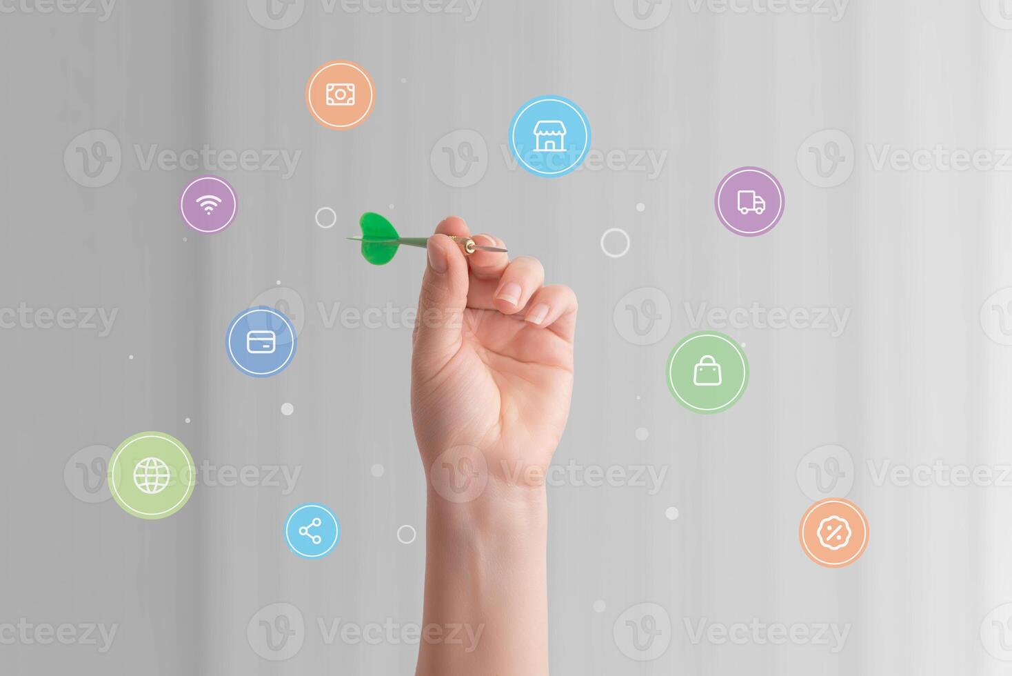 Hand holding a dart surrounded by various online shopping icons, symbolizing precision and strategy in targeting e-commerce goals and digital consumer engagement photo