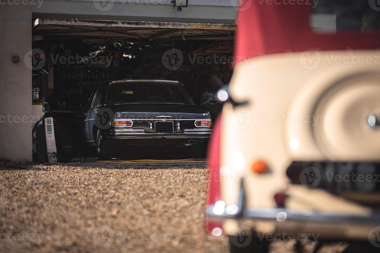 Vintage old car on a background of a garage where is another German luxury car is positioned. West Sussex, UK. photo
