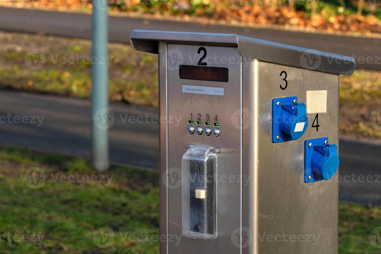 A sleek payment kiosk stands near a walking path in a public park photo