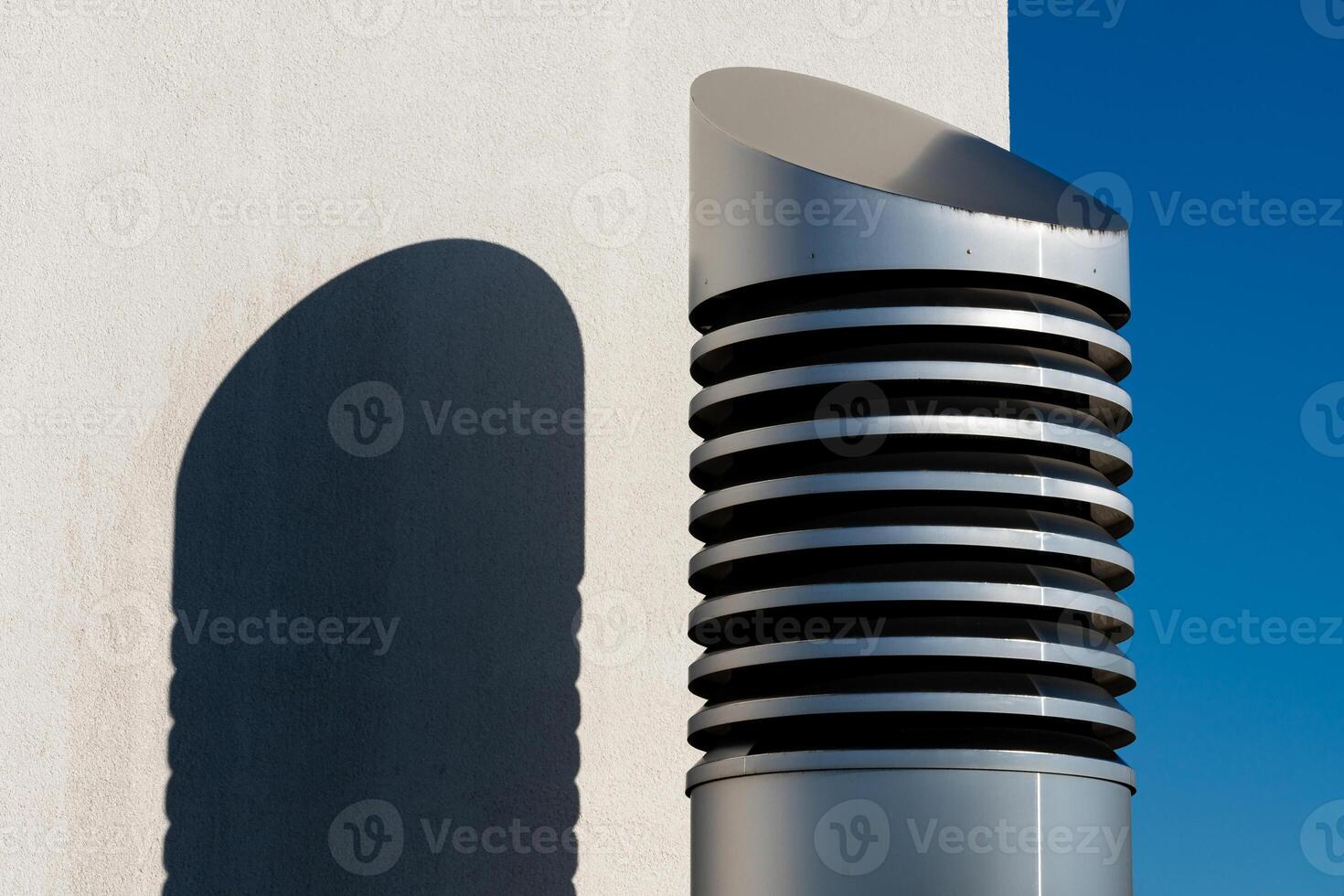 Modern ventilation cylindrical pipe casting shadow on wall photo