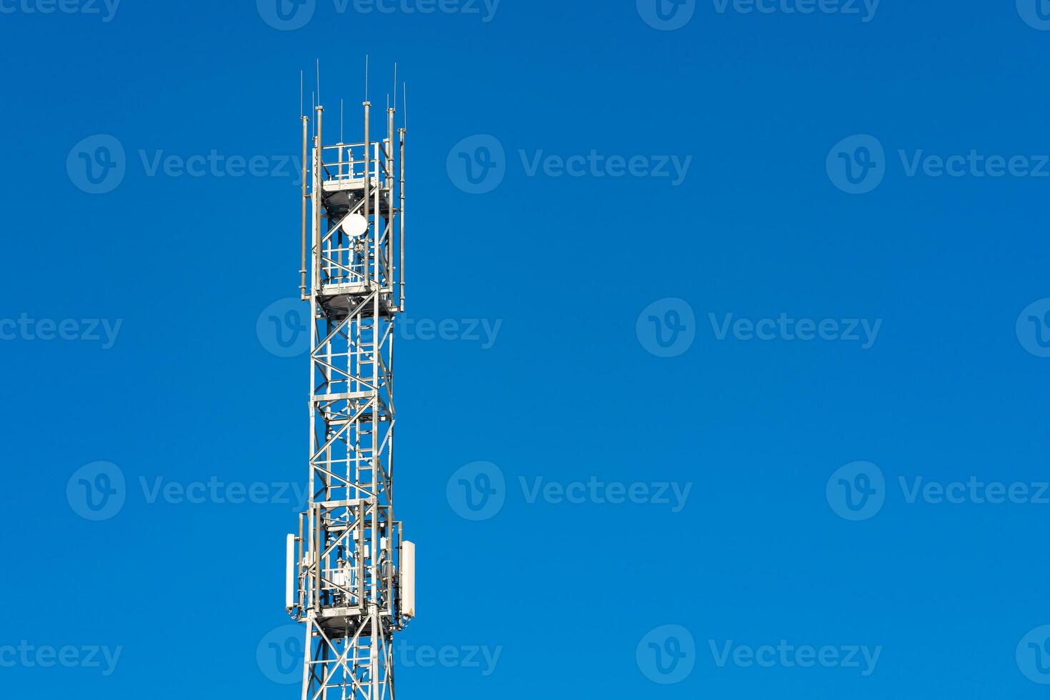 Telecommunication cell tower against clear blue sky in daylight photo