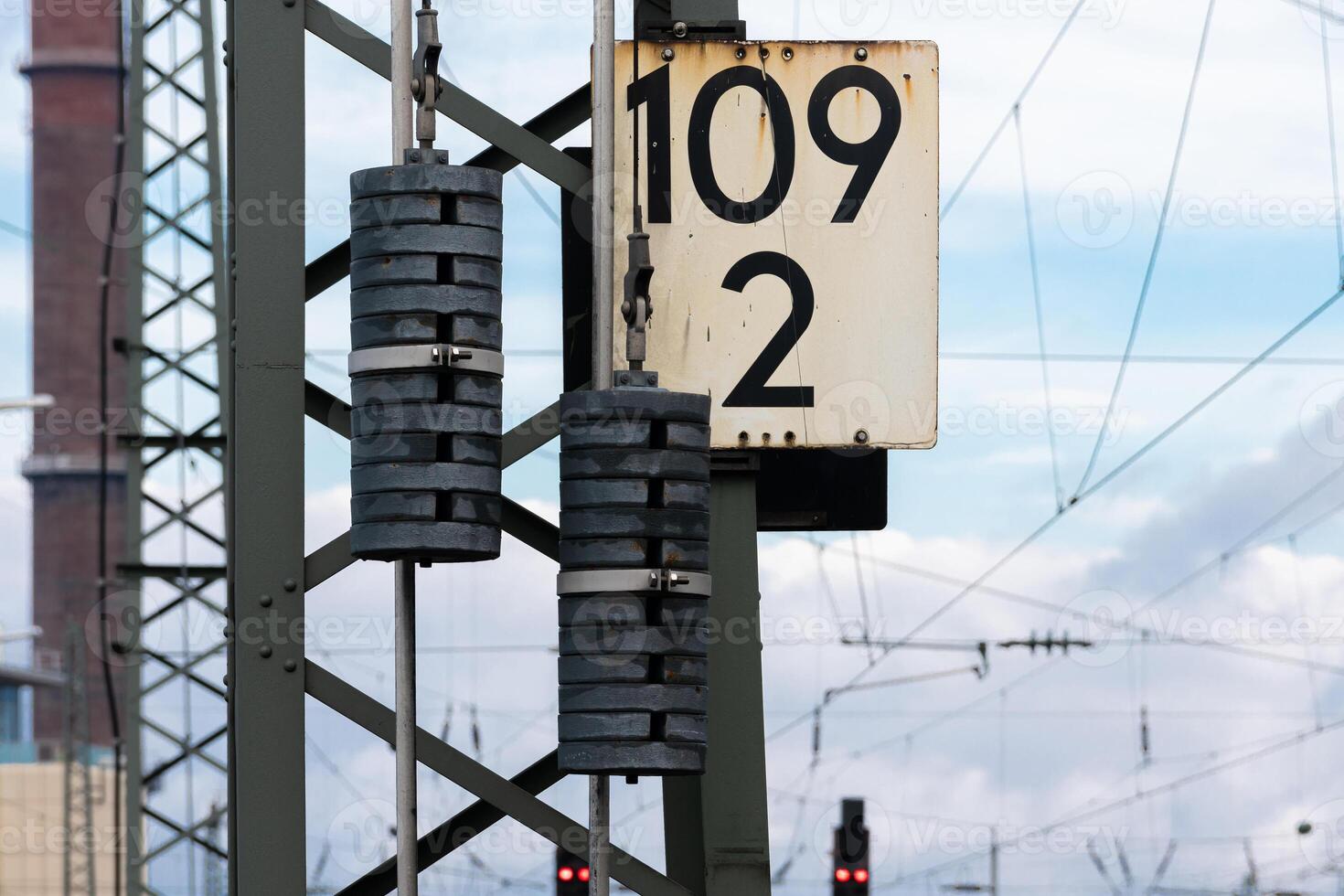 Railway signal post with numbered board and weight at station photo