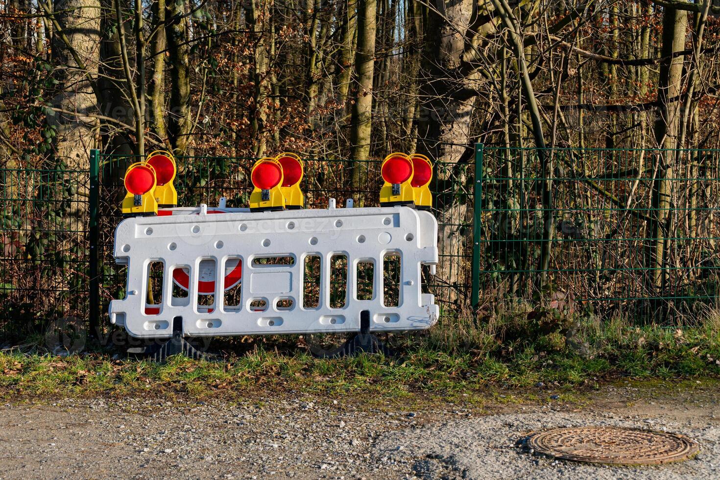 Construction barrier with warning lights placed near a wooded area photo
